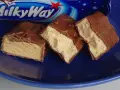 Czekoladowe batoniki Milky Way na niebieskim talerzu. Zastanawiasz się, ile kalorii ma Milky Way?