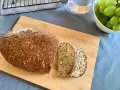 Keto chleb z twarogu i jajek z widocznymi ziarnami i orzechami, pokrojony na desce.