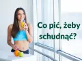 Uśmiechnięta kobieta w sportowym topie pije sok, zastanawiając się, co pić żeby schudnąć. Obok pomarańcza i jabłko.