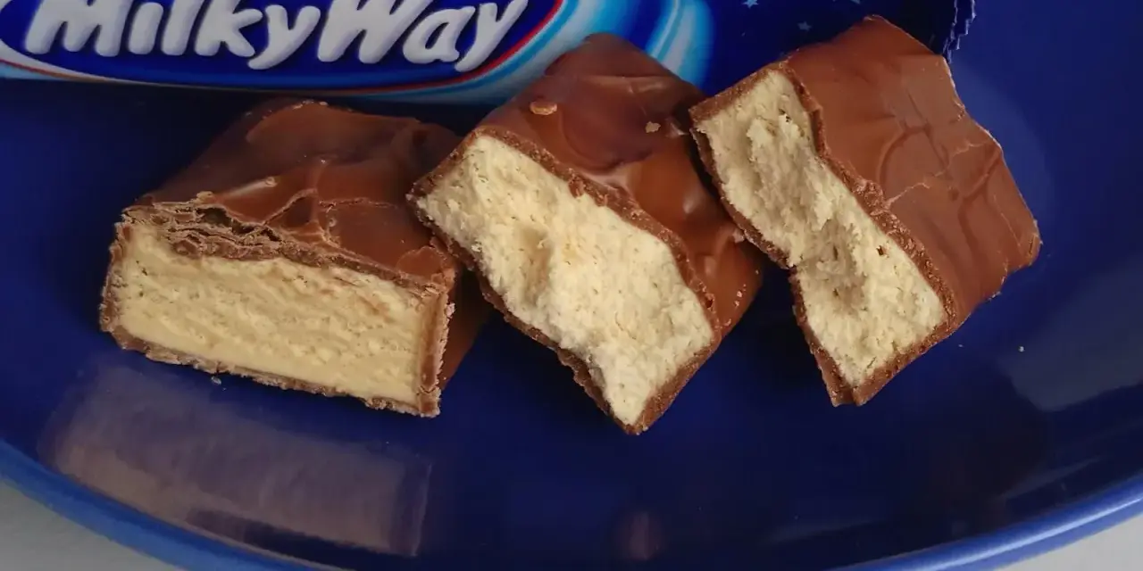 Czekoladowe batoniki Milky Way na niebieskim talerzu. Zastanawiasz się, ile kalorii ma Milky Way?