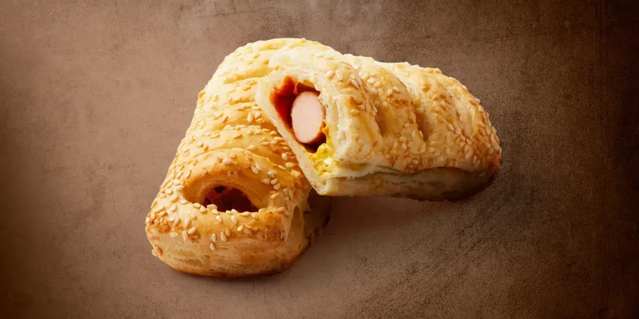 Pieczeni hot dog z Lidla, posypany sezamem, z widocznym parującym wnętrzem. Zastanawiasz się, ile kcal ma hot dog z Lidla?