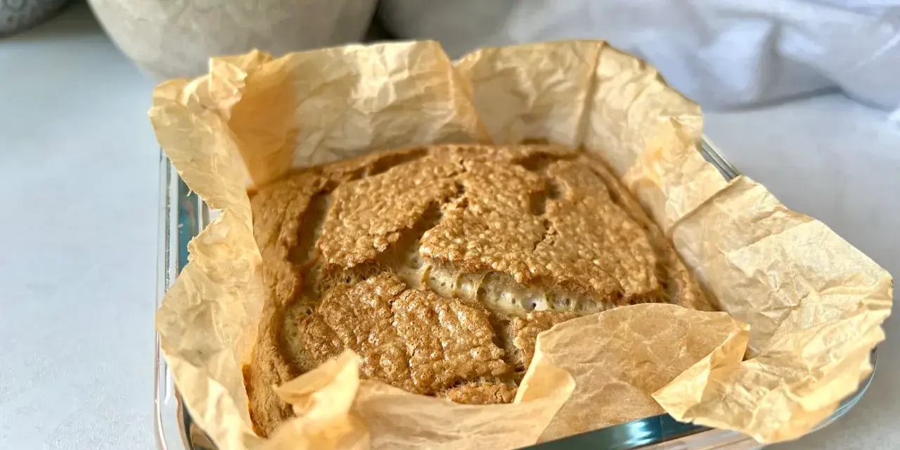 Świeżo upieczony chleb keto w papierze do pieczenia, z chrupiącą skórką i puszystym wnętrzem. Idealny na śniadanie.