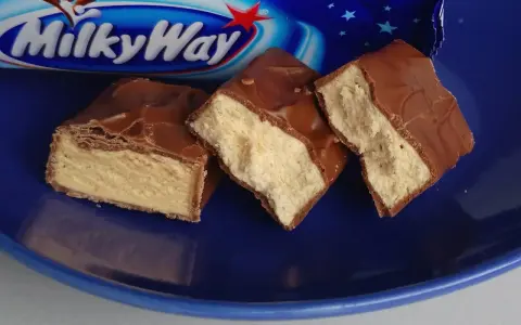 Czekoladowe batoniki Milky Way na niebieskim talerzu. Zastanawiasz się, ile kalorii ma Milky Way?