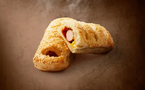 Pieczeni hot dog z Lidla, posypany sezamem, z widocznym parującym wnętrzem. Zastanawiasz się, ile kcal ma hot dog z Lidla?