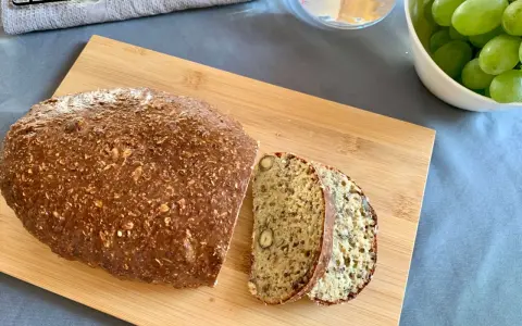 Keto chleb z twarogu i jajek z widocznymi ziarnami i orzechami, pokrojony na desce.