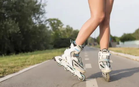 Nogi w rolkach na ścieżce rowerowej. Wspaniałe efekty jazdy na rolkach w letni dzień.