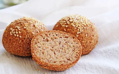 Proste keto bułki z sezamem, jedna przekrojona, ukazująca puszyste wnętrze. Idealne na dietę ketogeniczną.