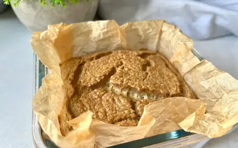 Świeżo upieczony chleb keto w papierze do pieczenia, z chrupiącą skórką i puszystym wnętrzem. Idealny na śniadanie.
