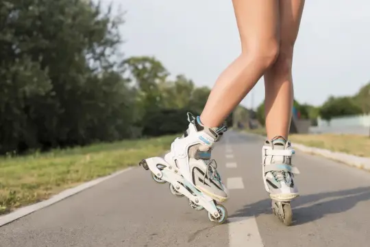 Nogi w rolkach na ścieżce rowerowej. Wspaniałe efekty jazdy na rolkach w letni dzień.