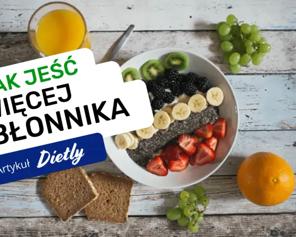 Jak jeść więcej błonnika? Miska pełna owoców, nasion chia i jagód, obok pieczywo pełnoziarniste i sok.