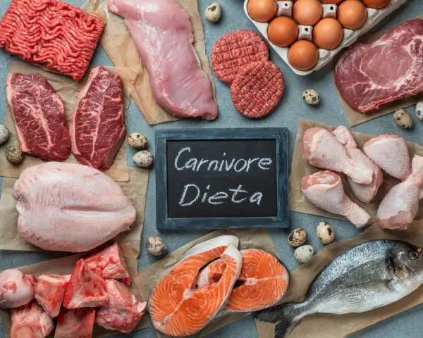 Różnorodne mięsa i ryby, jajka, kości. Tabliczka z napisem "Carnivore Dieta" sugeruje menu dla mięsożerców.