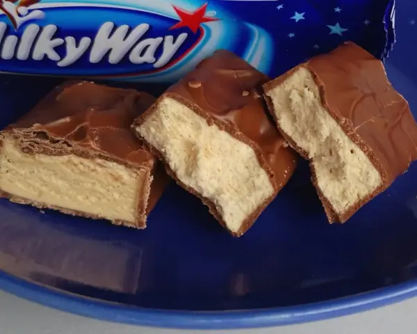 Czekoladowe batoniki Milky Way na niebieskim talerzu. Zastanawiasz się, ile kalorii ma Milky Way?