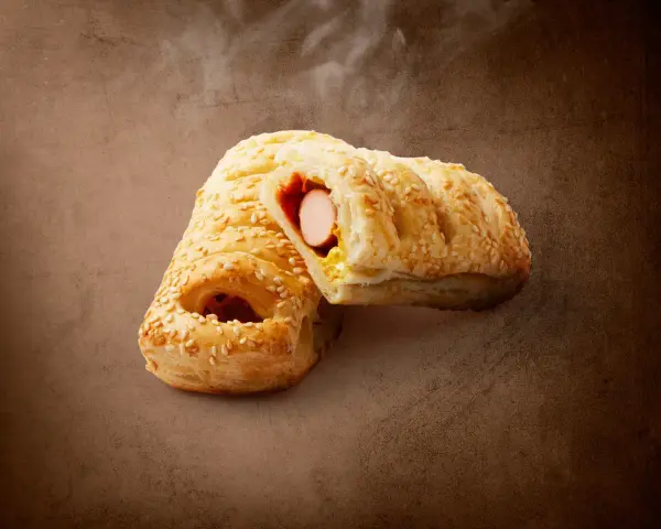 Pieczeni hot dog z Lidla, posypany sezamem, z widocznym parującym wnętrzem. Zastanawiasz się, ile kcal ma hot dog z Lidla?