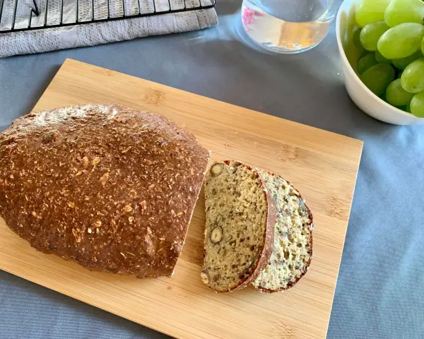 Keto chleb z twarogu i jajek z widocznymi ziarnami i orzechami, pokrojony na desce.