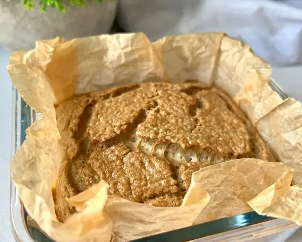 Świeżo upieczony chleb keto w papierze do pieczenia, z chrupiącą skórką i puszystym wnętrzem. Idealny na śniadanie.