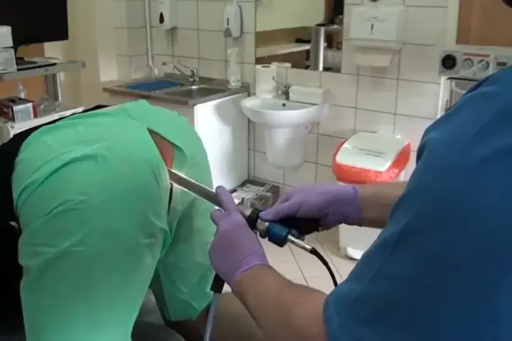 Lekarz w rękawiczkach wykonuje badanie jelit za pomocą endoskopu.
