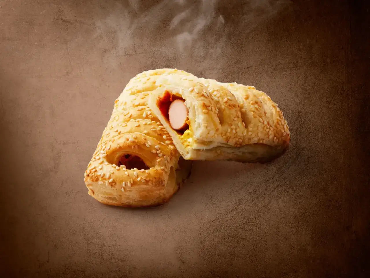 Pieczeni hot dog z Lidla, posypany sezamem, z widocznym parującym wnętrzem. Zastanawiasz się, ile kcal ma hot dog z Lidla?