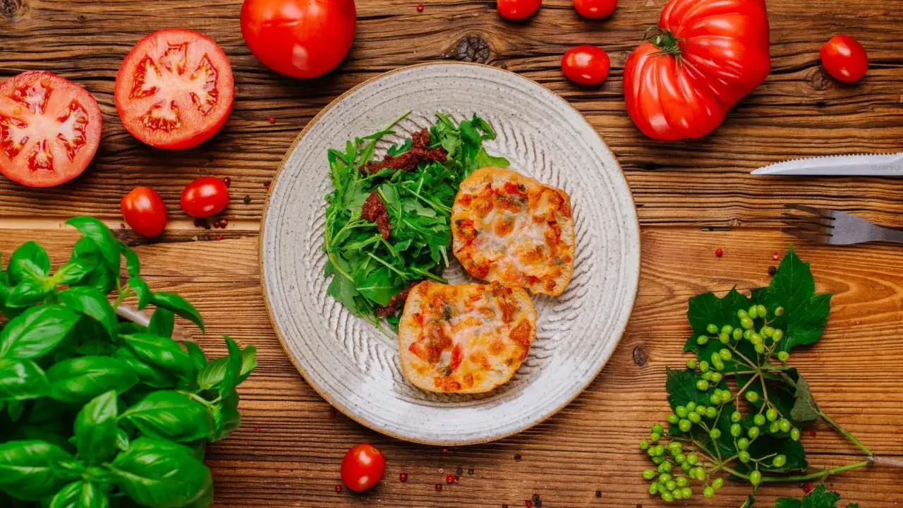 Keto-przyjazne przekąski z pomidorami, rukolą i serem na talerzu, otoczone świeżymi pomidorami i bazylią.