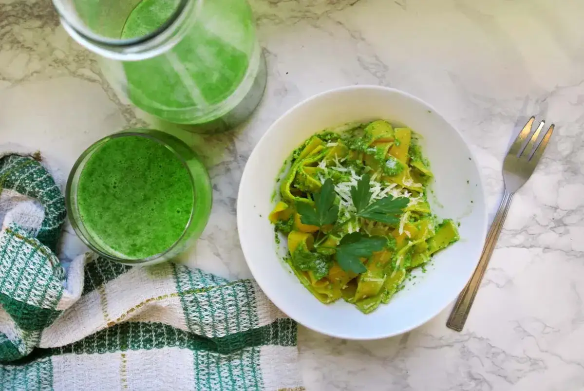 Makaron z zielonym pesto i parmezanem, obok szklanka i dzbanek zielonego smoothie. Czy pesto jest dietetyczne? Zależy od składników!